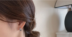 Gros plan d'une femme portant des créoles minimalistes à damier noir et blanc au design chic