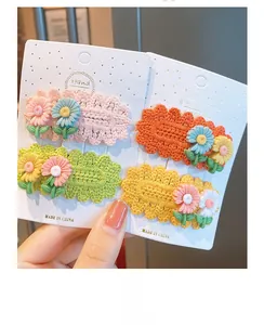 Close-up of handmade knitted daisy hair clips in vibrant pink and orange colors