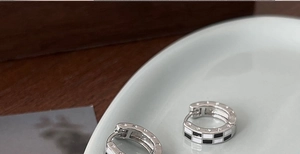 Vue macro des créoles en émail à damier noir et blanc avec gravure d'étoile sur le côté