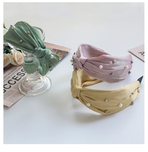 Detailed view of wide knotted fabric headbands with elegant pearl and silver bead embellishments