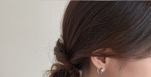 Gros plan de boucles d'oreilles créoles émaillées avec motif en damier noir et blanc