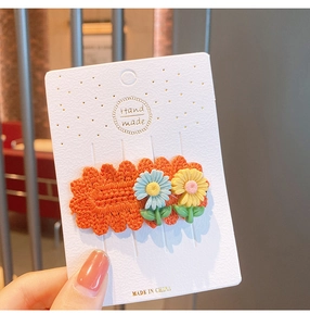 Detailed close-up of handmade knitted flower hair clip with daisy decor on display card