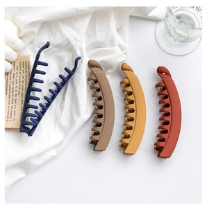 Detail of multi-color matte banana hair clips with internal teeth on a white fabric