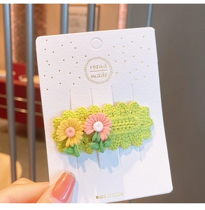 Close-up of handmade knitted daisy hair clips with floral texture on card packaging