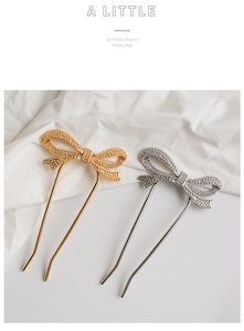 Detail of gold and silver bow-shaped U-shaped hairpins with textured finish on white fabric