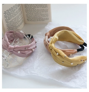 Detail of twisted fabric headband with delicate pleats, white pearls, and silver studs