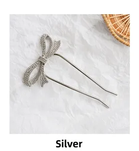 Close-up of a silver U-shaped hair stick featuring a sparkling rhinestone bow design