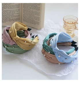 Close-up of pleated fabric headbands with pearl accents in assorted Morandi colors