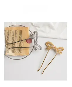 Detail of silver and gold bow hair pins with rhinestones on a minimalist U-shaped metal stick