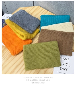 Detail showing various colors of ribbed knitted headbands stacked on a wooden surface