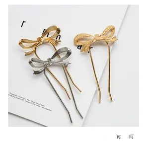 Detailed macro view of three minimalist metal bow hairpins in gold and silver finish