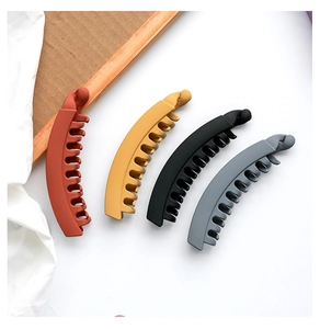 Close-up of four matte banana hair clips in orange yellow black and grey colors