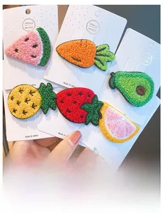 Detail of handmade knitted fruit hair clips including strawberry and avocado designs