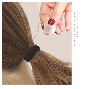Detail of elegant pearl hair clip and black spiral elastic band on brunette hair