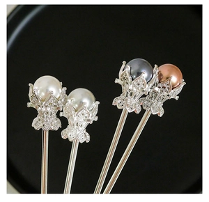 Détail de quatre épingles à cheveux argentées avec perles et couronnes de fleurs évidées