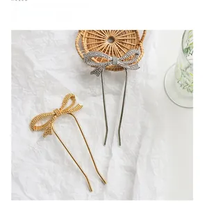 Detailed view of gold and silver bow-shaped U-shaped hair pins with textured metallic finish