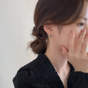 Boucles d'oreilles créoles à damier noir et blanc portées par un mannequin de près