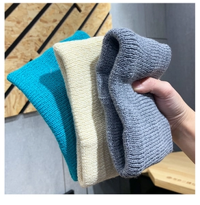 Detailed close-up of chunky knit headbands in lake blue, cream white, and dark gray colors