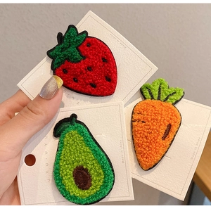 Detail of embroidered strawberry, avocado, and carrot patches with plush 3D texture