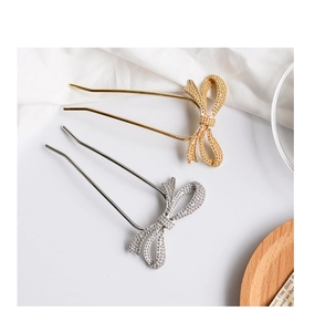 Detail of silver and gold U-shaped hair pins with sparkling glitter bow accents