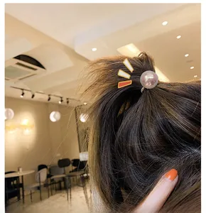 Close-up of a ponytail hook featuring a large pink gradient pearl on a hair tie for women