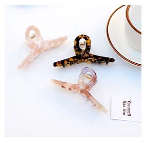 Detailed view of three large acetate hair claws in marble, tortoiseshell and amber patterns