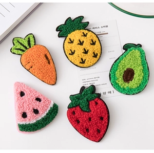 Detail of colorful fruit-shaped knitted hair clips featuring carrot and strawberry designs