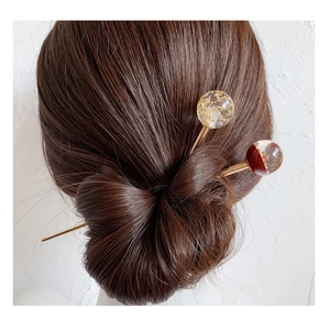 Détail de pics à cheveux dorés avec sphères en résine et feuilles d'or en chignon