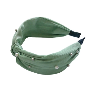 Light green twisted fabric headband with decorative white pearls and silver beads on white background