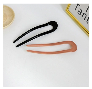 Detail of minimalist U-shaped hair pins in black and nude pink colors on a white background