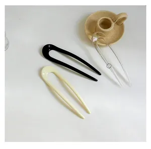 Close-up of three U-shaped resin hair pins in black, cream white and transparent clear