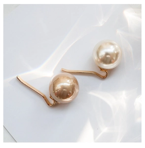Detailed close-up of elegant pearl hair pins in white and champagne gold on a white card
