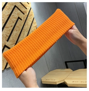 Close-up of bright orange ribbed knit headband showing stretchable texture and elasticity