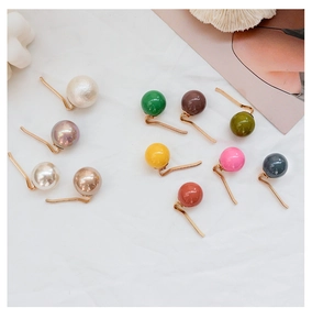 Collection of colorful faux pearl hair clips and pins on an elegant white textured background