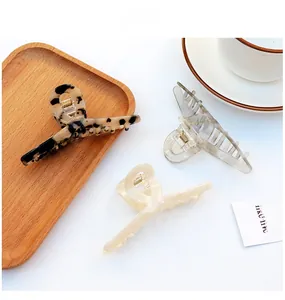 Detailed view of large acetate hair claws in leopard, translucent grey and cream colors