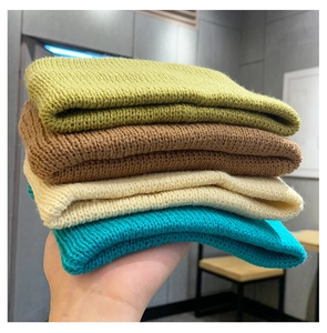 Close-up of four thick knitted beanies in green, caramel, beige, and blue colors