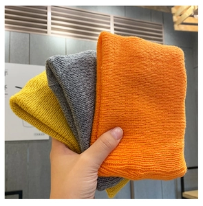 Close-up of thick knitted textures in orange, grey, and yellow for autumn beanie styles