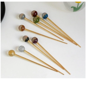 Détails d'élégantes épingles à cheveux dorées avec boules de résine étoilées colorées