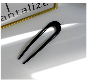 Detail view of the polished black resin U-shaped hair pin with a smooth mirror finish