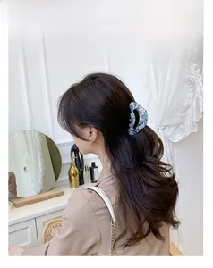 Detail of large floral acetate hair claw clip holding hair in a ponytail hairstyle