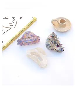 Three acetate hair claws with iridescent and marbled patterns on a clean white surface