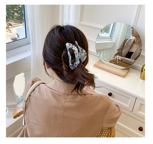 Detail of elegant large acetate hair claw clip with blue marble pattern on female hair