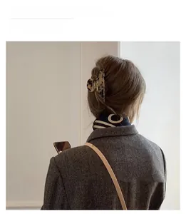 Detail of tortoiseshell patterned hair claw clip on model in autumn winter outfit