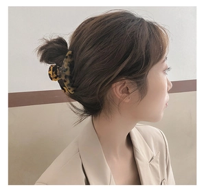 Detail of elegant leopard print acetate hair claw clip worn on a half-up hairstyle