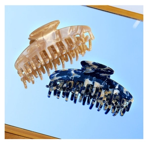Close-up of large marble blue and pearl champagne acetate hair claws on a blue surface