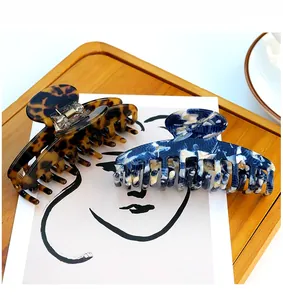 Large acetate hair claws in tortoiseshell and blue marble texture on a wooden tray