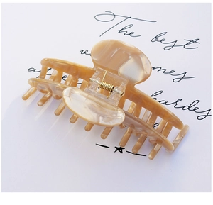 Close-up of a large marbled acetate hair claw with gold spring and champagne texture
