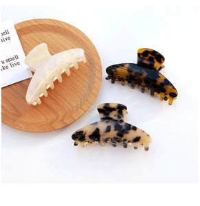 Macro detail of acetate hair claws in beige pearl, dark tortoiseshell and leopard patterns