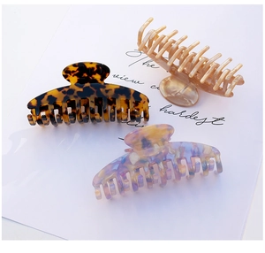 Three acetate hair claws in dark tortoiseshell, pearl beige, and marble patterns