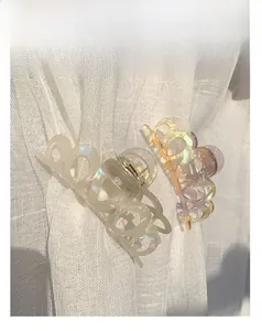 Detail of two iridescent pearlescent hair claws in white and amber on soft fabric